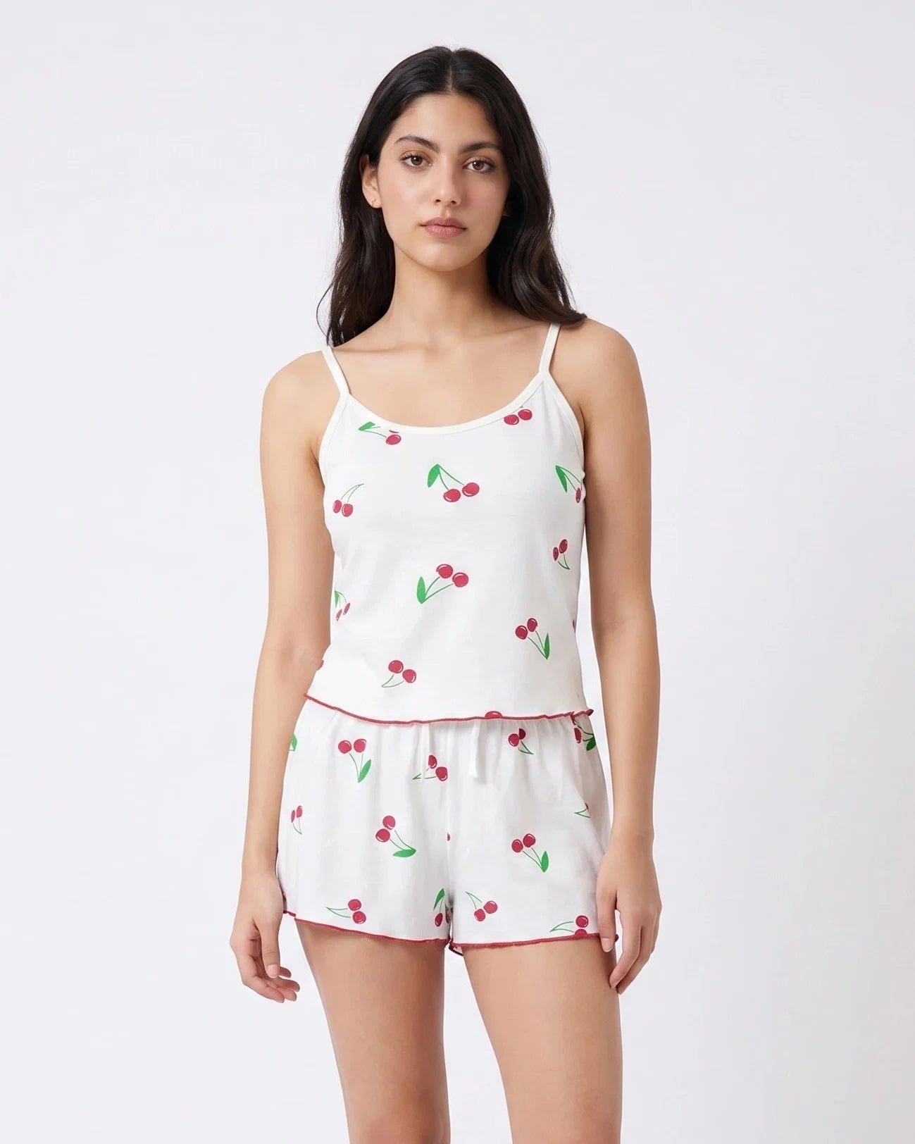 Woman wearing a white pajama set with cherry pattern on a white background